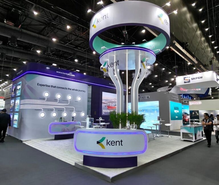 A circular overhead sign and illuminated curved counter in a purple and white exhibition stand.