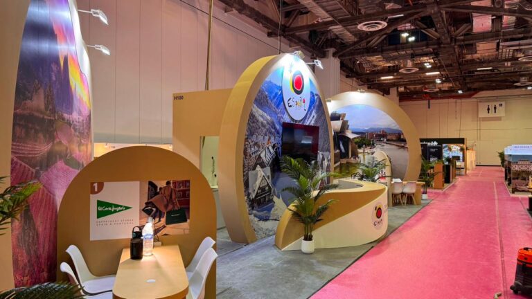 A yellow exhibition pavilion with rounded structures, landscape graphics and a curved reception counter.