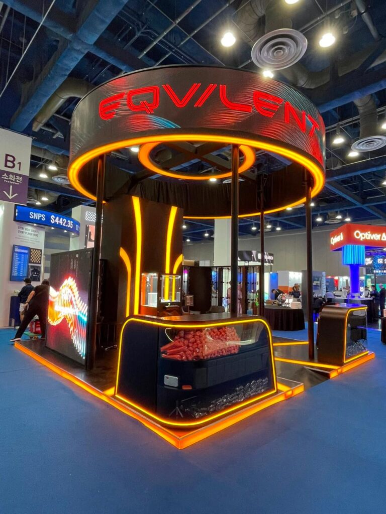 A black exhibition stand with a circular canopy and orange illuminated frames.