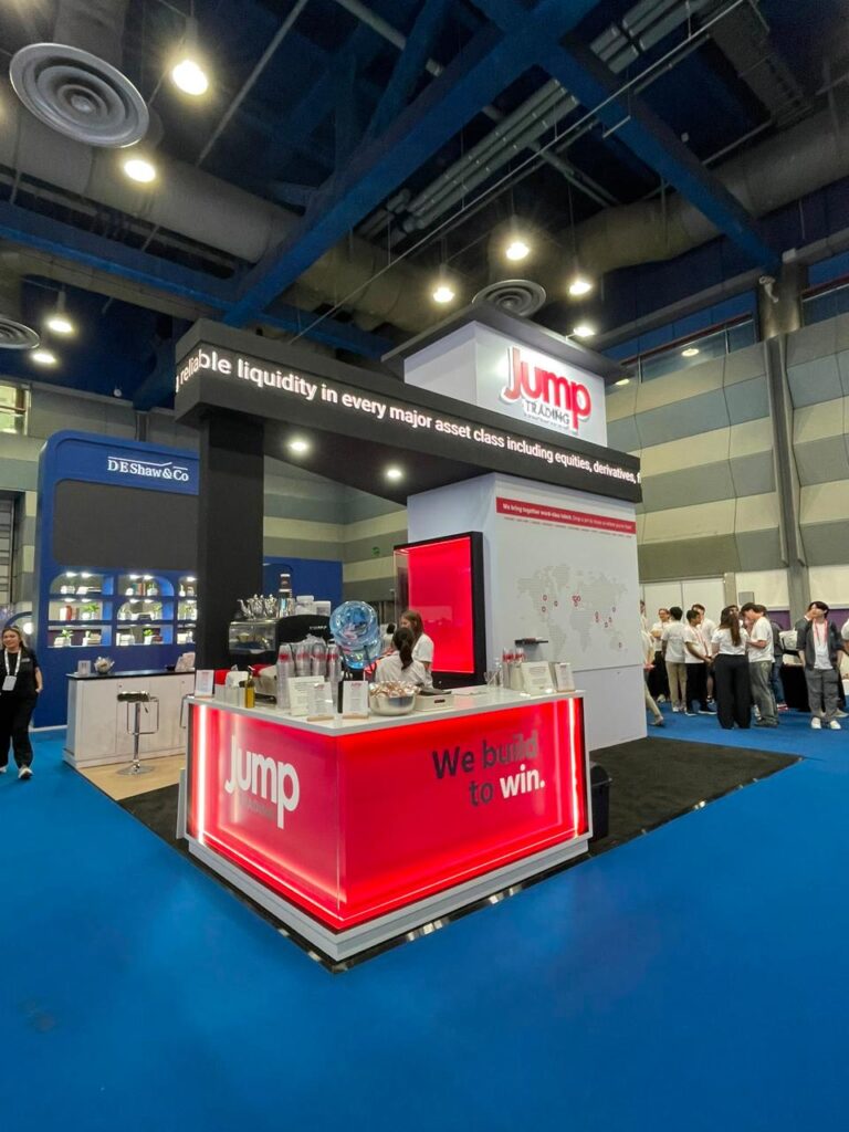 A compact red and white corner exhibition stand with product displays and a reception counter.
