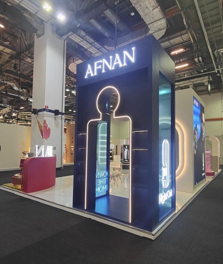 A fragrance exhibition stand with a tall blue illuminated display, bottle graphics and a small counter.