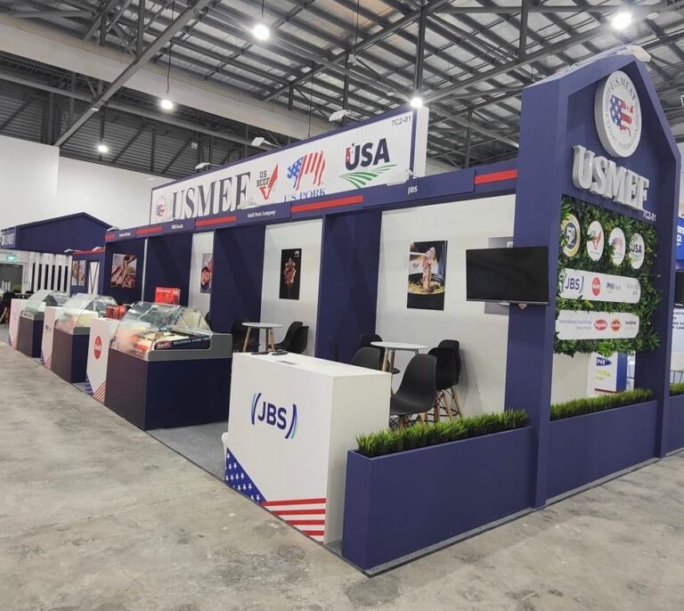 A navy and white exhibition pavilion with overhead signage, display counters and meeting seats.