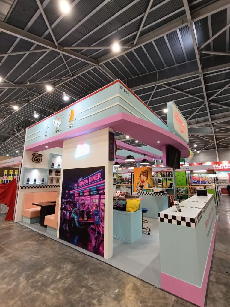 A pink and white exhibition stand with a square overhead frame and illuminated product displays.