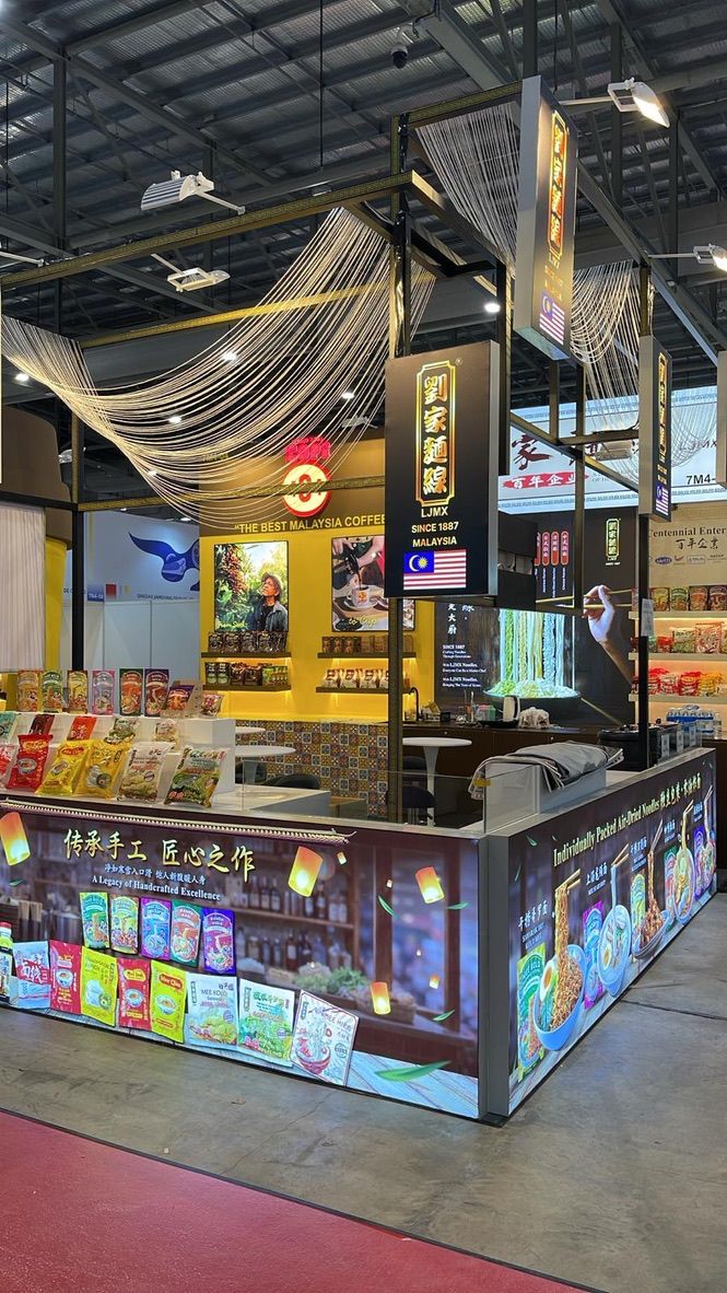 A black and gold exhibition stand with a draped canopy and colourful product display panels.